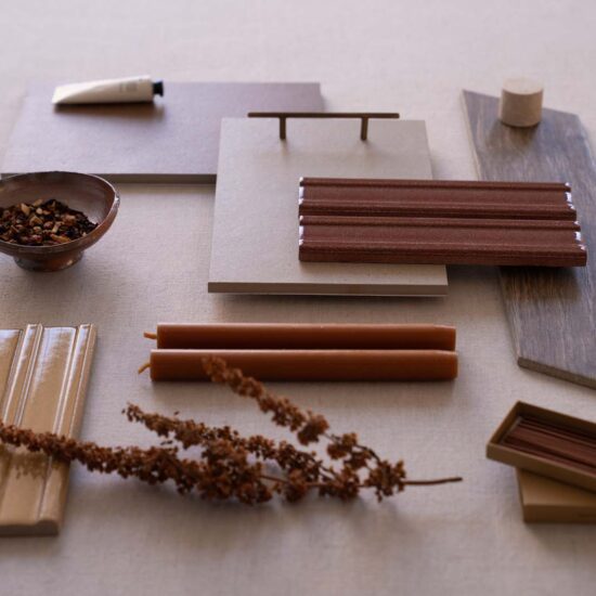 Various samples of tiles in warm tones, with glossy and matte finishes, arranged on a table.