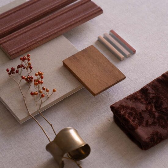 Selection of material samples, including dove-colored tiles and a wooden panel, arranged on a light fabric.