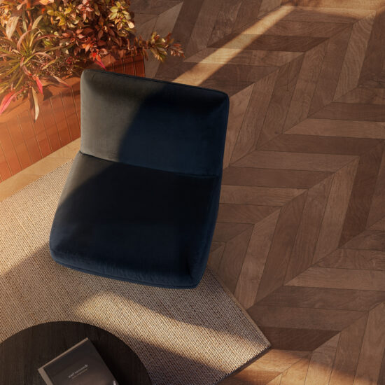 Ambiente accogliente con pavimento in gres porcellanato effetto legno, tonalità calde e texture geometrica.