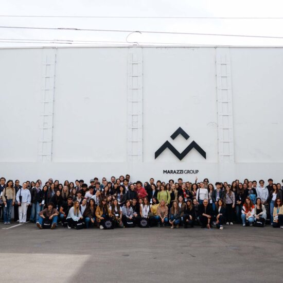 A group of about 150 people posing in front of the white wall with the "Marazzi Group" logo prominently displayed.