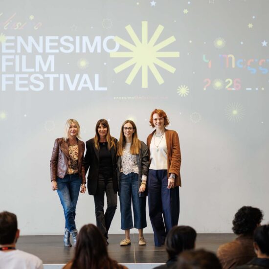 Quattro donne sorridenti si presentano su un palco con il logo dell'Ennesimo Film Festival sullo sfondo.